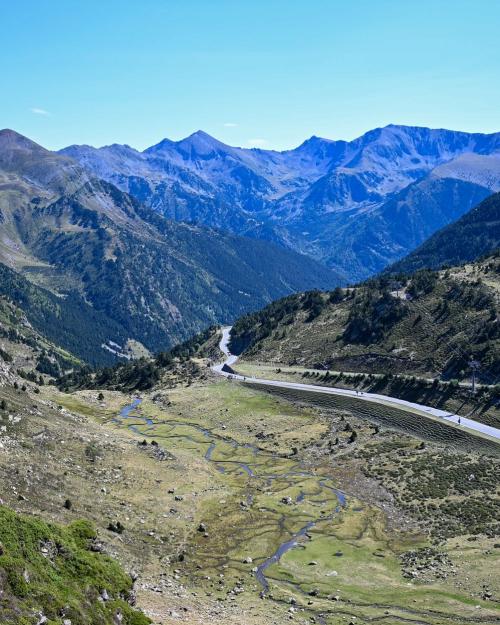 Aerial view of a winding road cutting through the lush Pyrenees mountains.