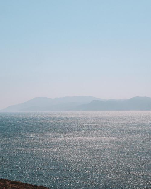 Peaceful view of the Aegean Sea with distant Greek islands under a clear sky.
