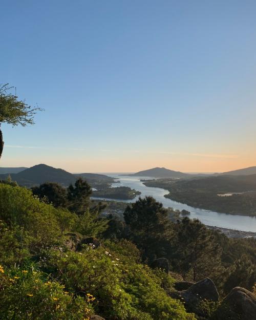 Idyllic sunset view over the Minho River with lush greenery and rolling hills.