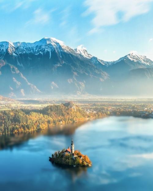Majestic Lake Bled with church on island, surrounded by Julian Alps under sunset light.