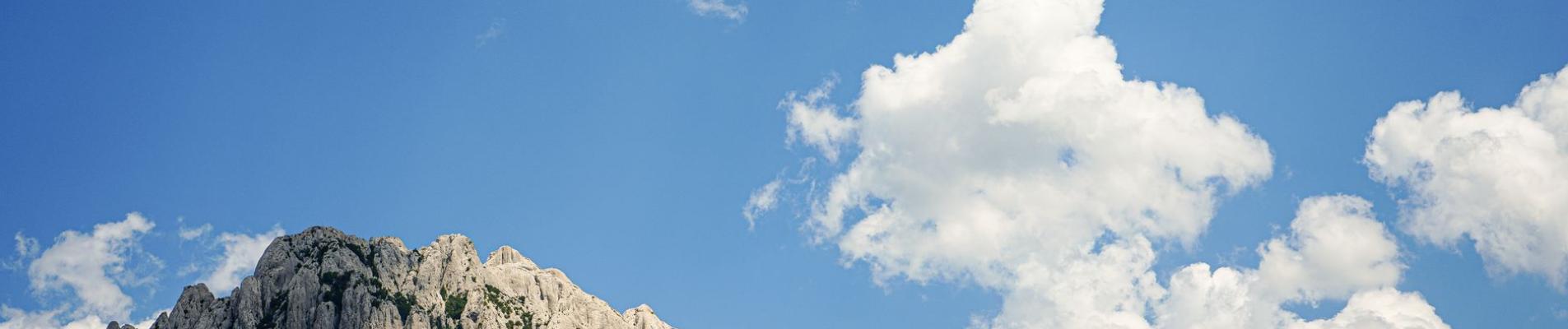 Stunning view of a rocky mountain range under a vibrant blue sky with fluffy clouds.