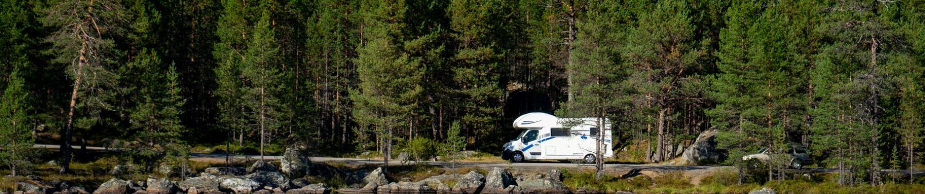 Beautiful lake reflection of forest and camper van in Troms, capturing serene nature.