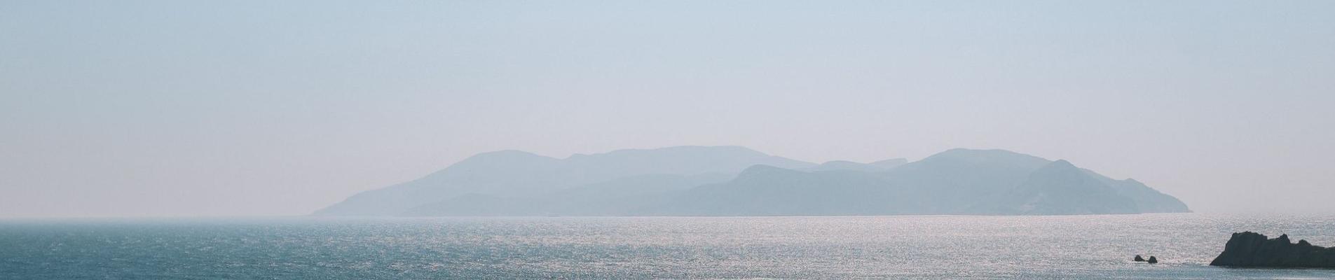 Peaceful view of the Aegean Sea with distant Greek islands under a clear sky.