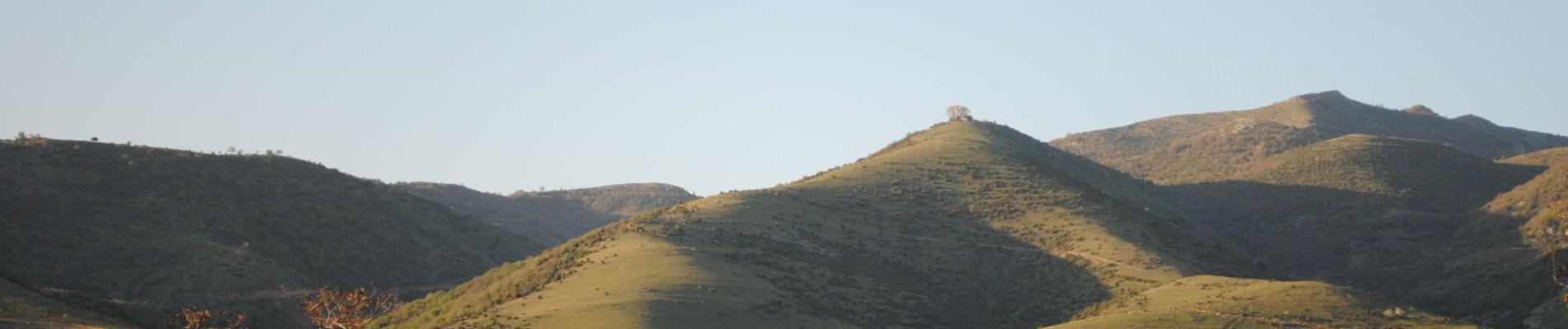 Peaceful countryside view of green hills under a clear sky in Serres, Greece.