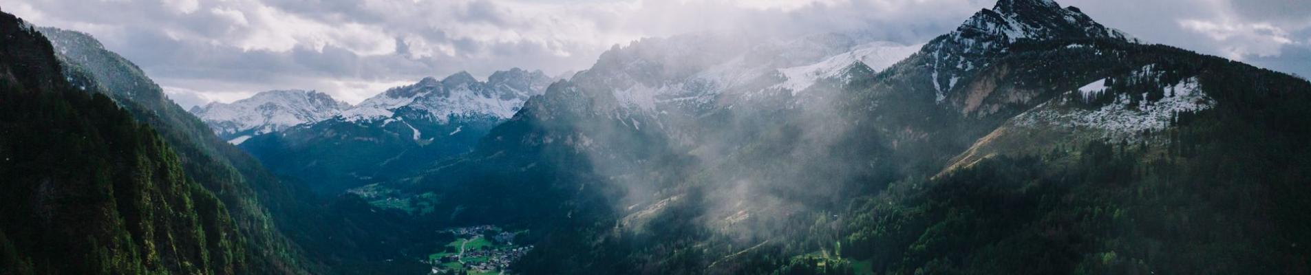 A stunning aerial shot of Canazei in the Dolomites, surrounded by lush greenery and dramatic mountains.
