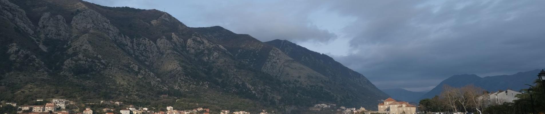 Peaceful morning view of Kotor Bay in Montenegro, showcasing calm waters and mountainous backdrop.
