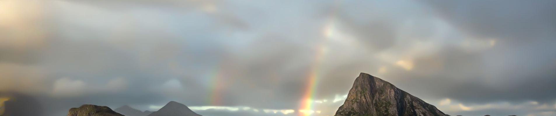 Scenic view of a rainbow arching over the rugged coastline of Offersøya, Nordland, Norway.