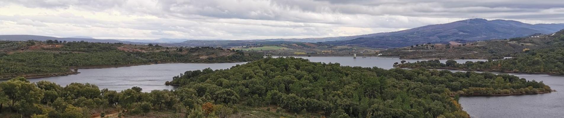 Serene view of lush greenery and a winding river in Bragança District, Portugal, under a cloudy sky.
