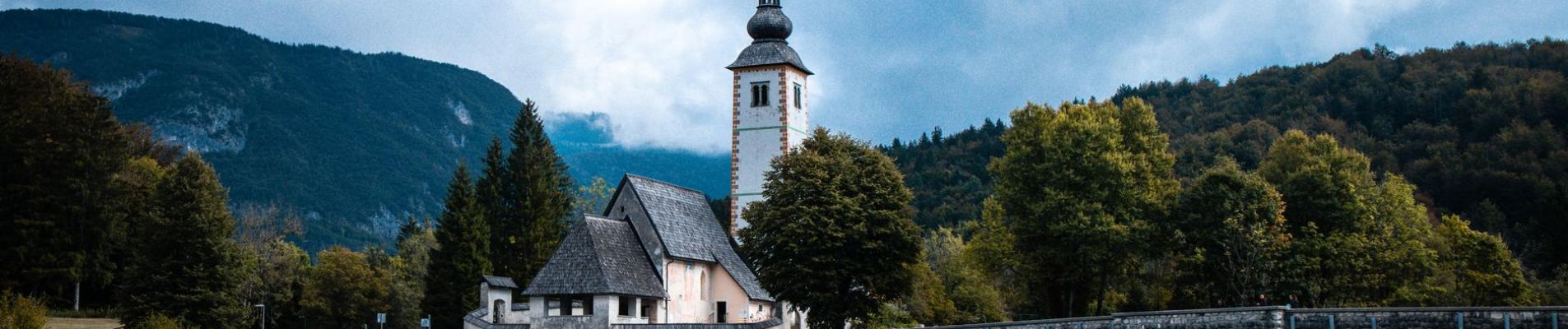 Picturesque view of St. John the Baptist Church and bridge over Lake Bohinj in Slovenia.