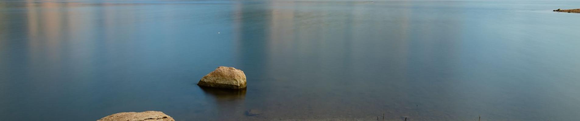 Tranquil scene of Sau Reservoir with majestic mountains under clear skies.