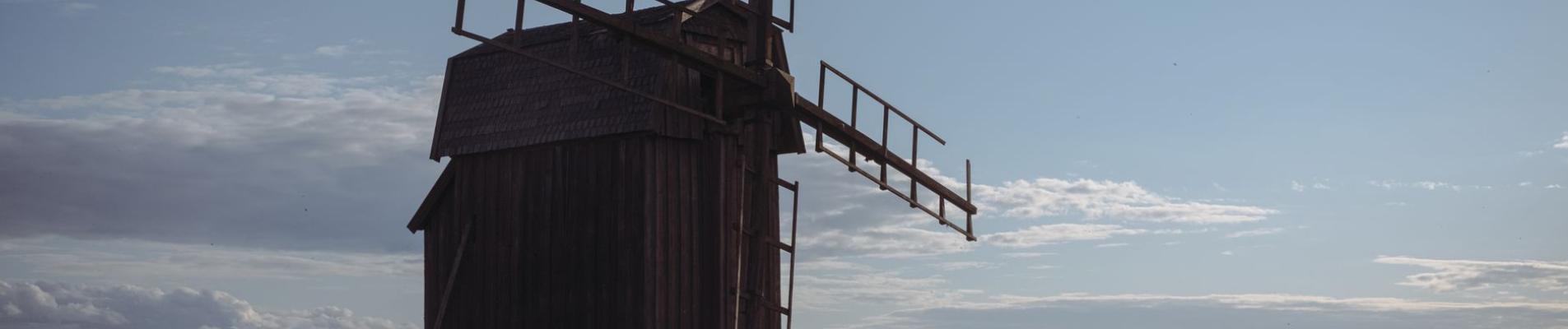 A traditional wooden windmill stands alone in the scenic Swedish countryside during a sunny day.