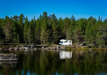 Beautiful lake reflection of forest and camper van in Troms, capturing serene nature.