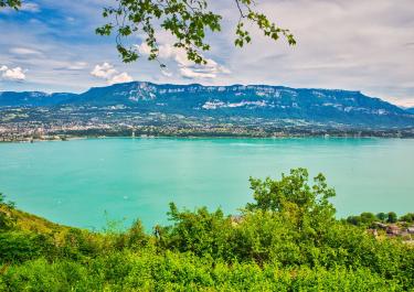 Experience the tranquil beauty of Lake Bourget surrounded by the majestic French Alps in Auvergne-Rhône-Alpes, France.