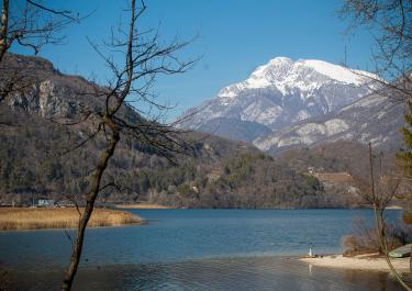 Breathtaking winter landscape of Lago di Cavazzo with snowy mountains in Friuli-Venezia Giulia, Italy.