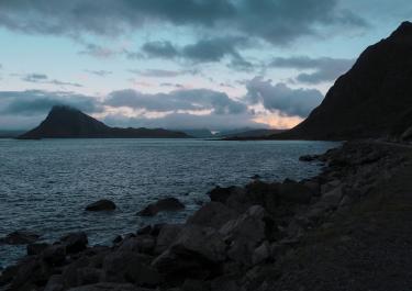 Picturesque scenery of rocky coast of rippling lake and silhouettes of rough mountains